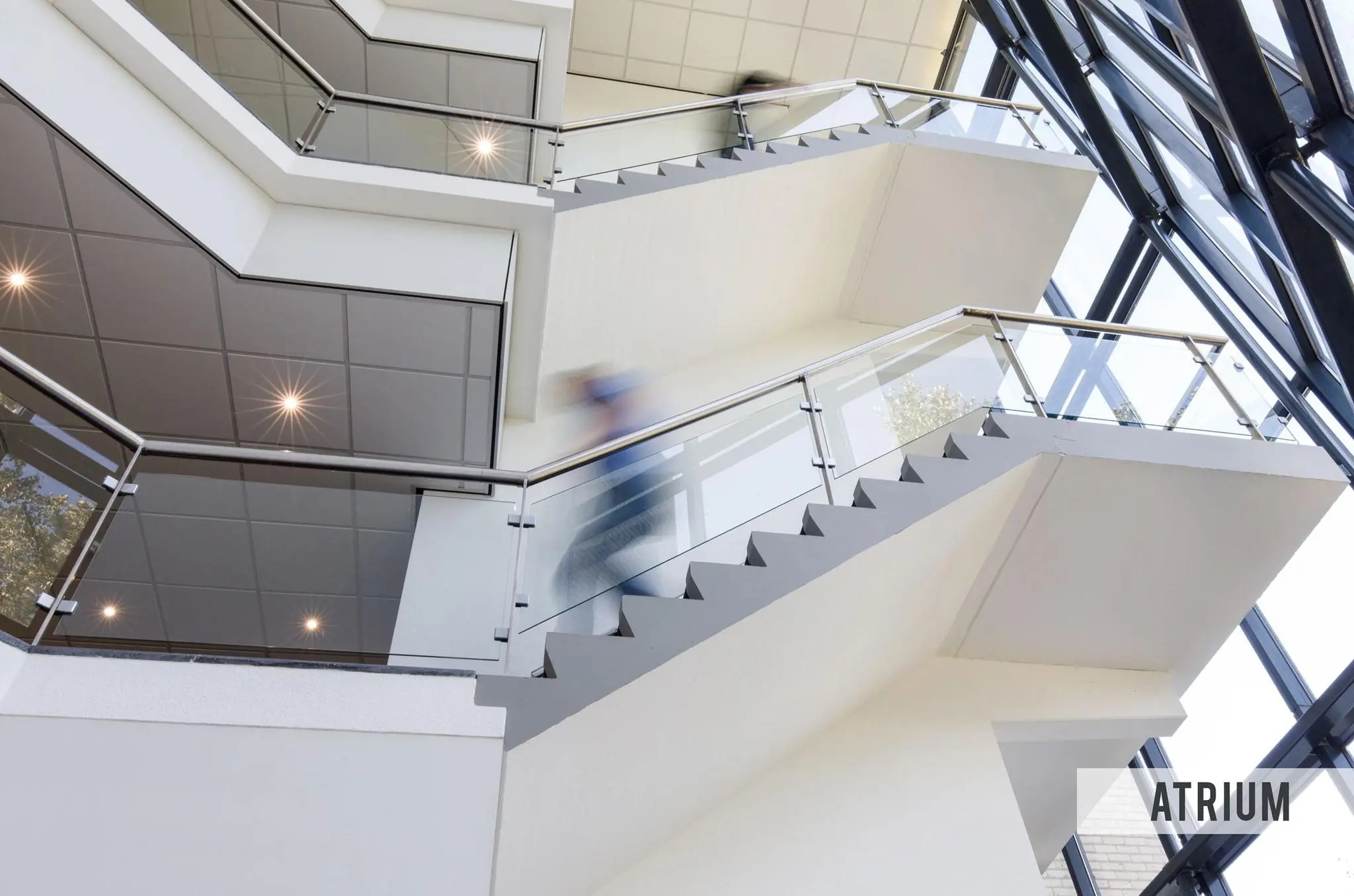 Moderne trap met glazen leuningen in het atrium van een gebouw aan de Baarnsche Dijk.